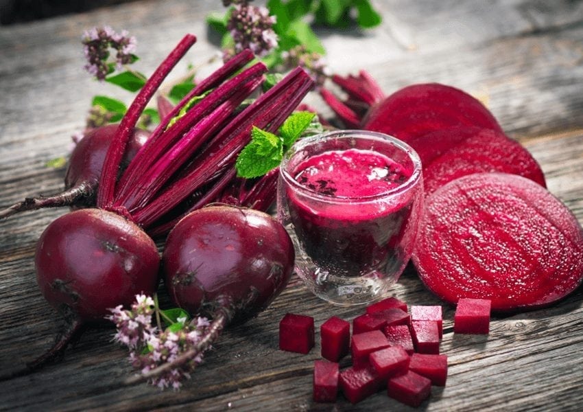 Beetroots and beetroot juice on a brown wooden table