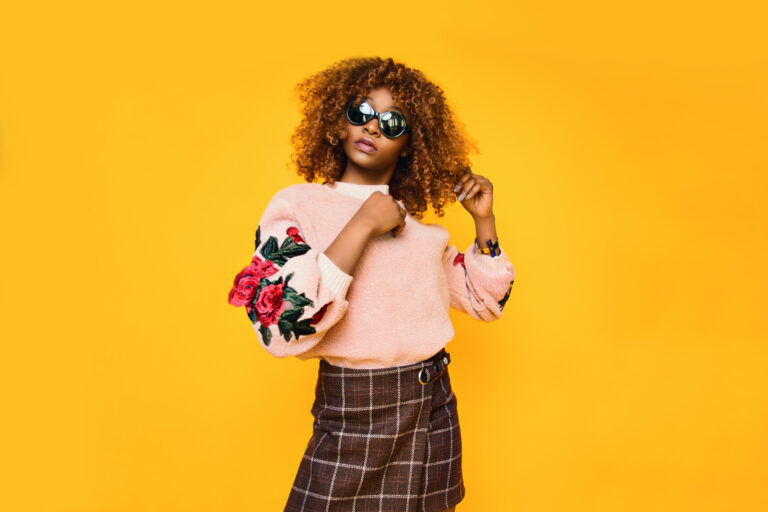 Female model wearing sunglasses on a yellow background