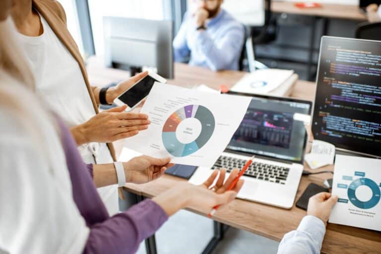 People holding a printed pie chart and viewing data to make business decisions