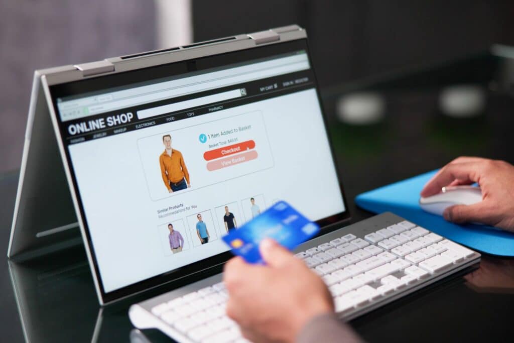Person viewing clothes on a online store and holding a credit card to purchase.