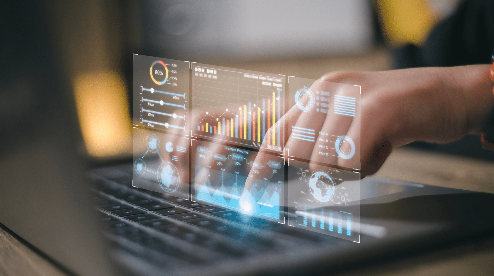 Person typing on a laptop keyboard. A series of digital chart infographics hover over the keyboard.